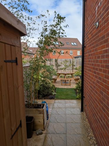 A serene backyard with a wooden picnic table and garden plants.