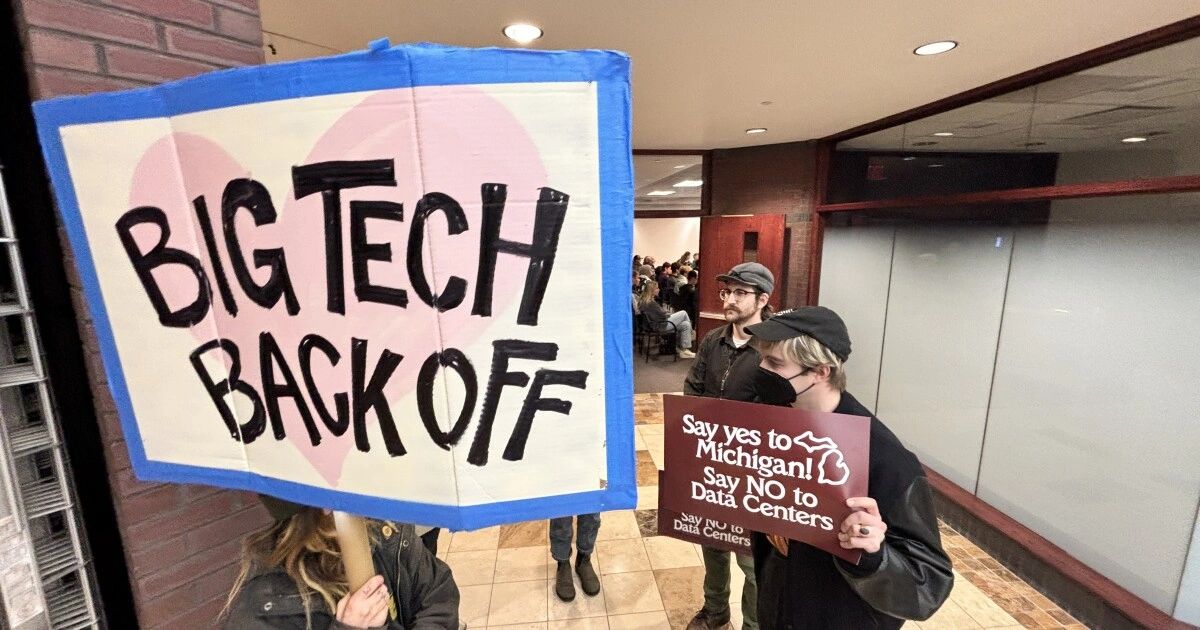 Protesters hold signs against big tech and data centers in Michigan.