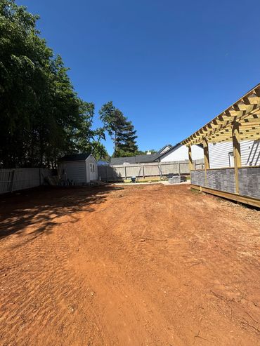 Backyard with a shed, fencing, and a pergola under a clear blue sky.