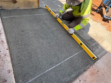 Worker leveling fresh concrete with a spirit level.