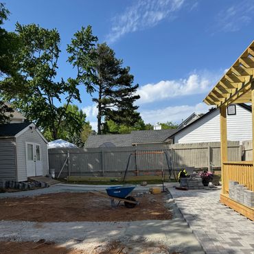 Backyard under construction with paving and swing set.