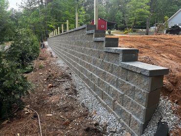 Newly built stone retaining wall with posts.
