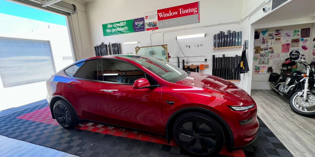 Red Tesla with tinted windows inside a workshop.