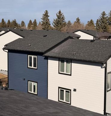 Modern townhouses with contrasting blue and white siding under clear skies.
