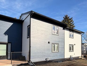 Two-tone house exterior with blue and white siding under a clear sky.