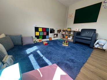 Cosy room with arm chair and baby toys in book shelf