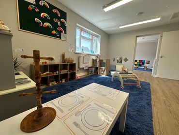 Role play corner on large carpet area. Small climbing frame and children’s art work on the walls