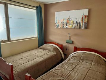 Cozy bedroom with two single beds and cityscape painting.