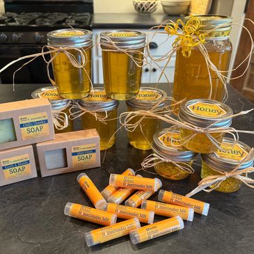 Various jars of honey, natural soaps, and lip balms displayed on a kitchen counter.