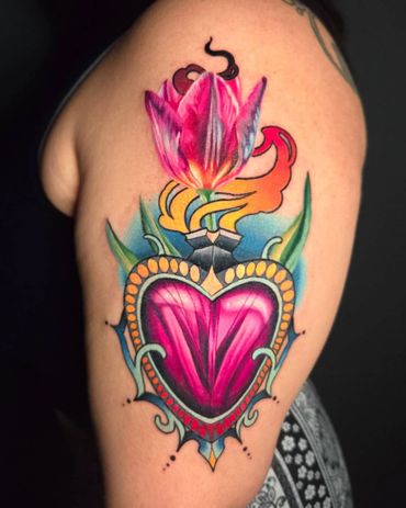 Colorful tattoo of a heart with a blooming flower and decorative elements on the arm.