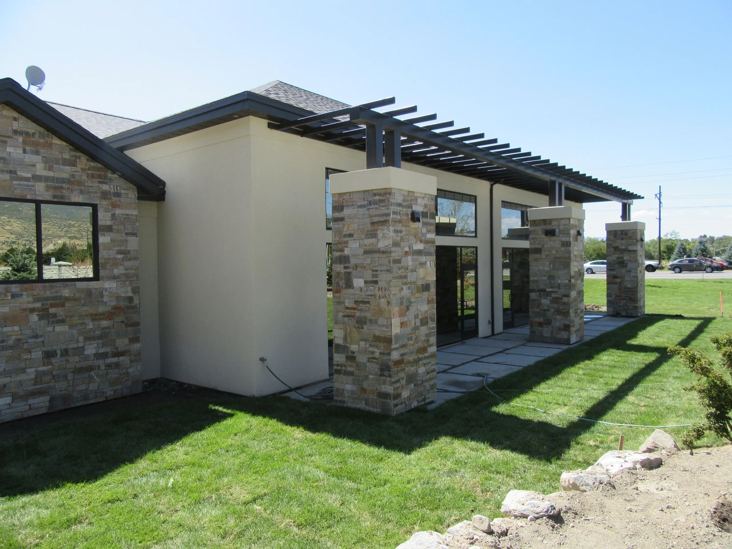 Side view of a commercial building. It features beige stucco & columns with beige and brown stones.
