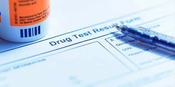 Close-up of a drug test results form with a pen and a medicine bottle.