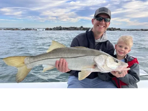 a man and boy holding a snook caught while inshore fishing