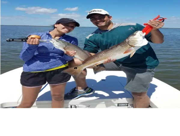 couple holding redfish caught on inshore fishing trip