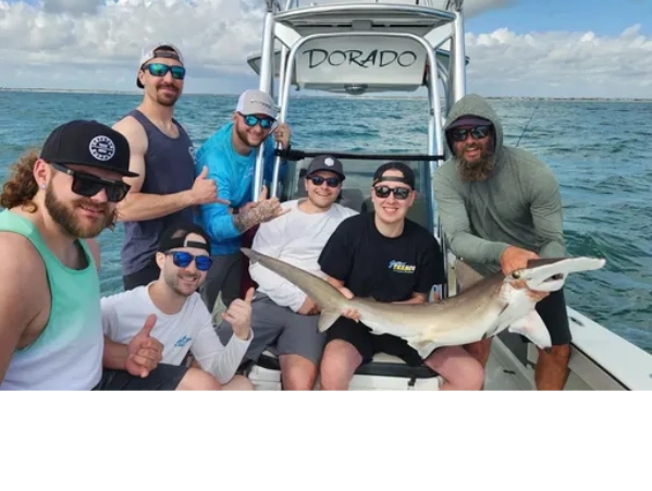 group of happy clients holding hammerhead shark caught on a shark fishing trip