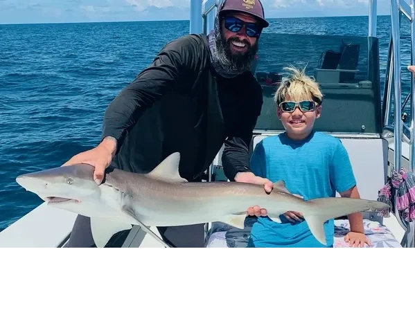 2 happy clients  caught a shark while shark fishing