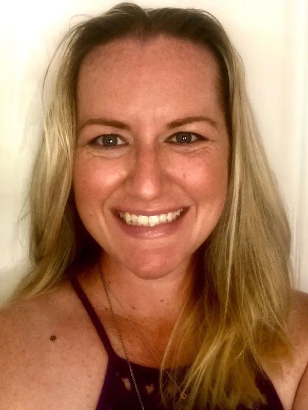 Smiling woman with long blonde hair and a dark tank top.