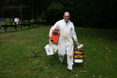 Joe Zgurzynski, beekeeper at Country Barn Farm, walking with hive equipment to inspect the apiary.