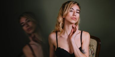 Woman in black lingerie posing with a reflection on a dark background.