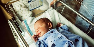 Newborn baby sleeping peacefully in a hospital bassinet.