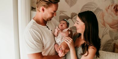 New parents joyfully hold their newborn baby at home.