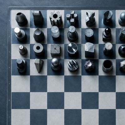 Overhead chessboard with unfamiliar metal pieces in rows