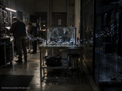 Two people examining broken glass and wiring in a server room