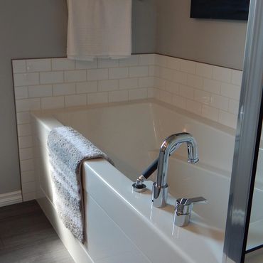 Modern bathtub with chrome faucet and towels in a clean bathroom.