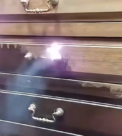 Light reflecting off a wooden drawer handle.