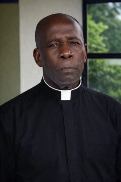 Portrait of a serious African American priest in clerical attire.