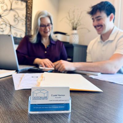 Business card of an accountant with two people consulting in the background.