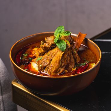 Spicy chicken curry garnished with fresh mint leaves in a rustic bowl.