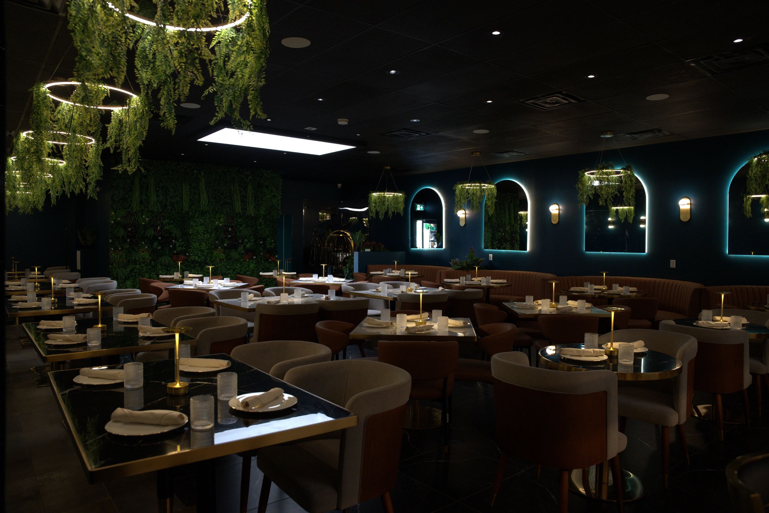 Elegant restaurant interior with modern lighting and green plants.
