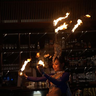 A performer dances with flaming props in a dimly lit bar.