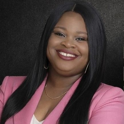 Confident woman smiling in a pink blazer against a dark background.