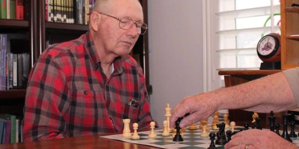 Two elderly men playing chess indoors.