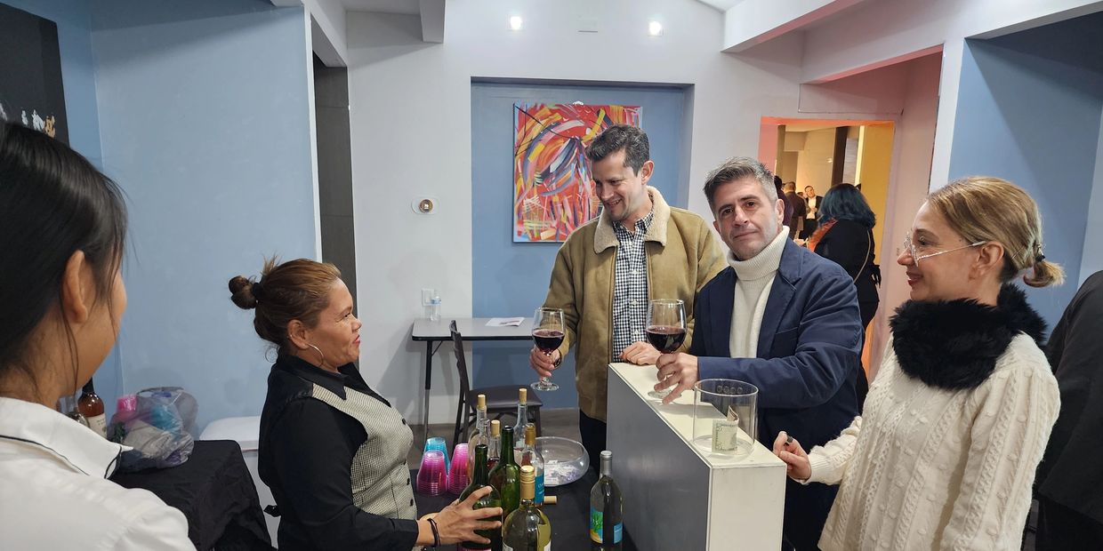 Group of people smiling gathering around the bar ordering drinks.