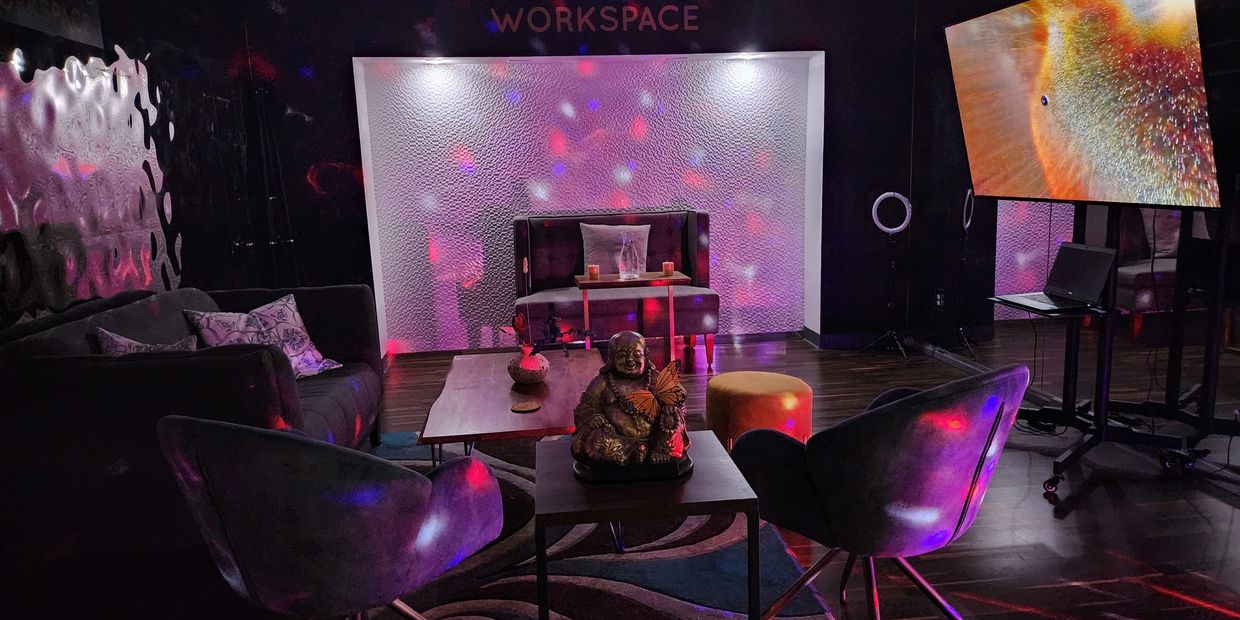 The podcasting studio with chairs, coffee table, sofas, lights and 75" rolling monitor.
