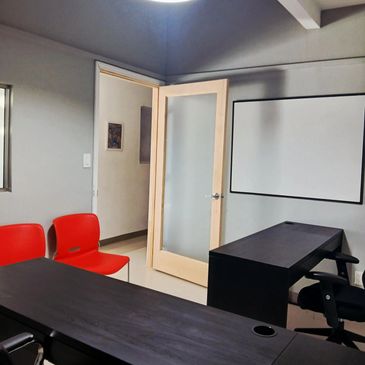 Private office showing a lockable keyed door with two desks, chairs, white board and charging statio