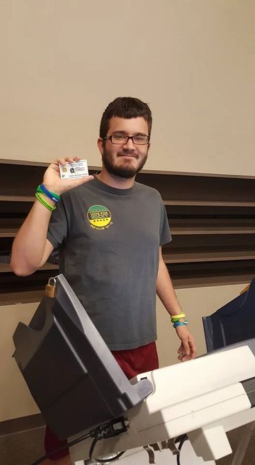 Young man standing behind a ballot machine.