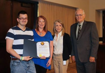 Group of 4 people standing with Autism Awareness Month proclamation.
