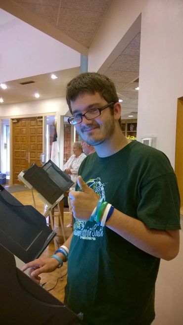Young man behind a voting booth.