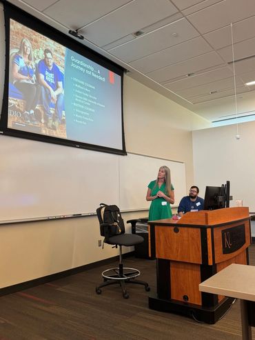 Woman standing behind lectern looking up at presentation.