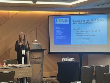 Woman standing behind lectern presenting.
