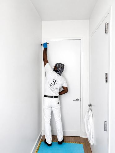 Painter working on a white door in a minimalist room.