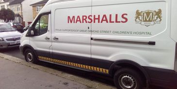 White Marshalls service van parked on a residential street.
