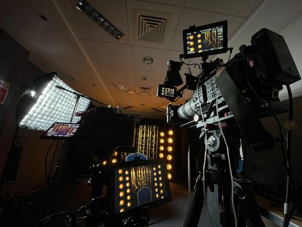 Professional video cameras and lighting setup in a studio.