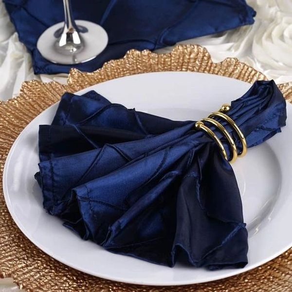 Elegant navy blue napkin with gold ring on white plate and textured gold charger.
