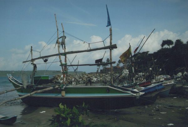 Traditional fishing boats docked on a beach under a blue sky.