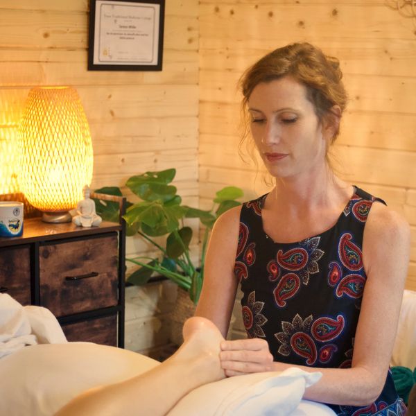 Woman giving a foot massage in a cozy, warmly lit room.